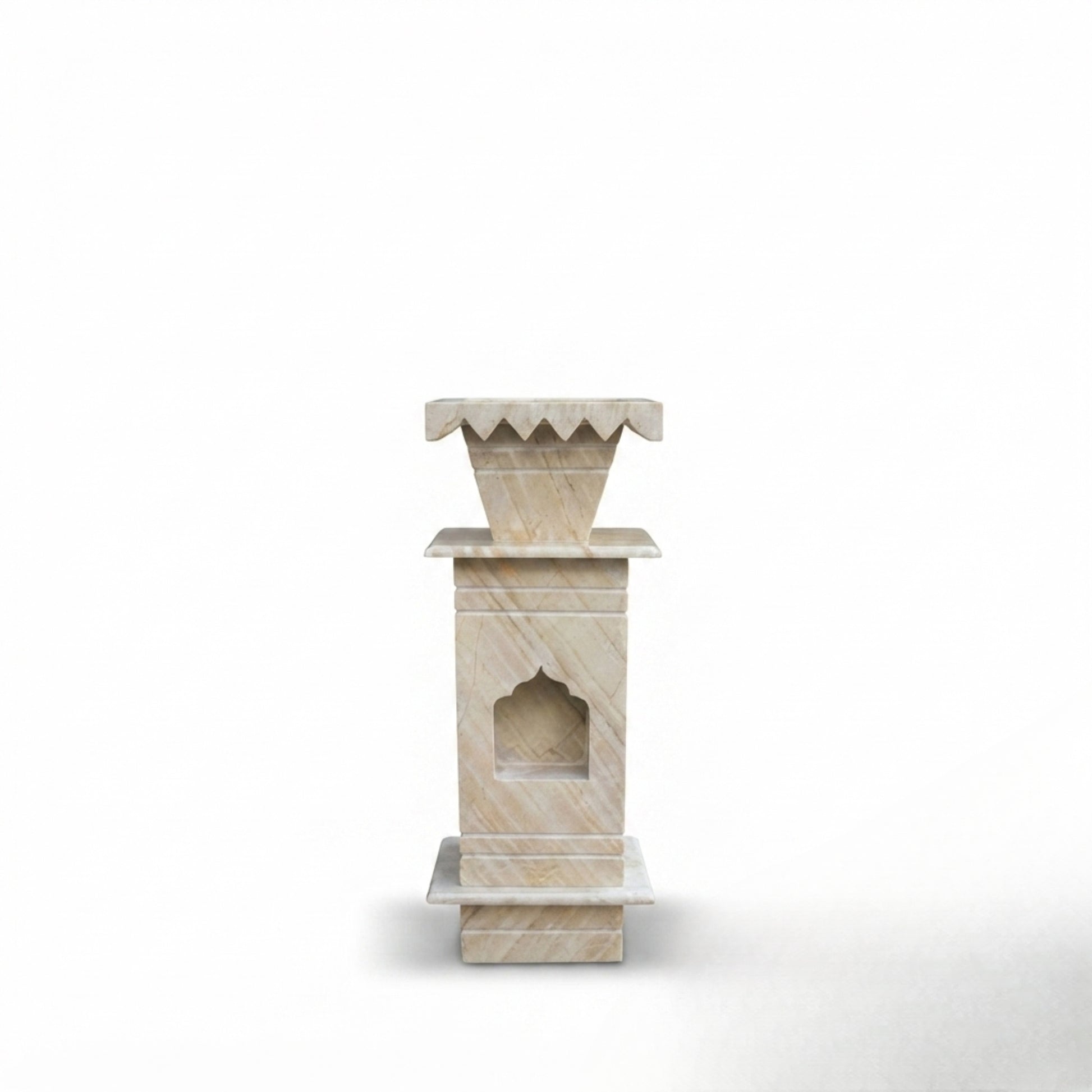 A small beige stone decorative pedestal or miniature altar with layered rectangular tiers and a carved arched niche, centered on a clean white background.