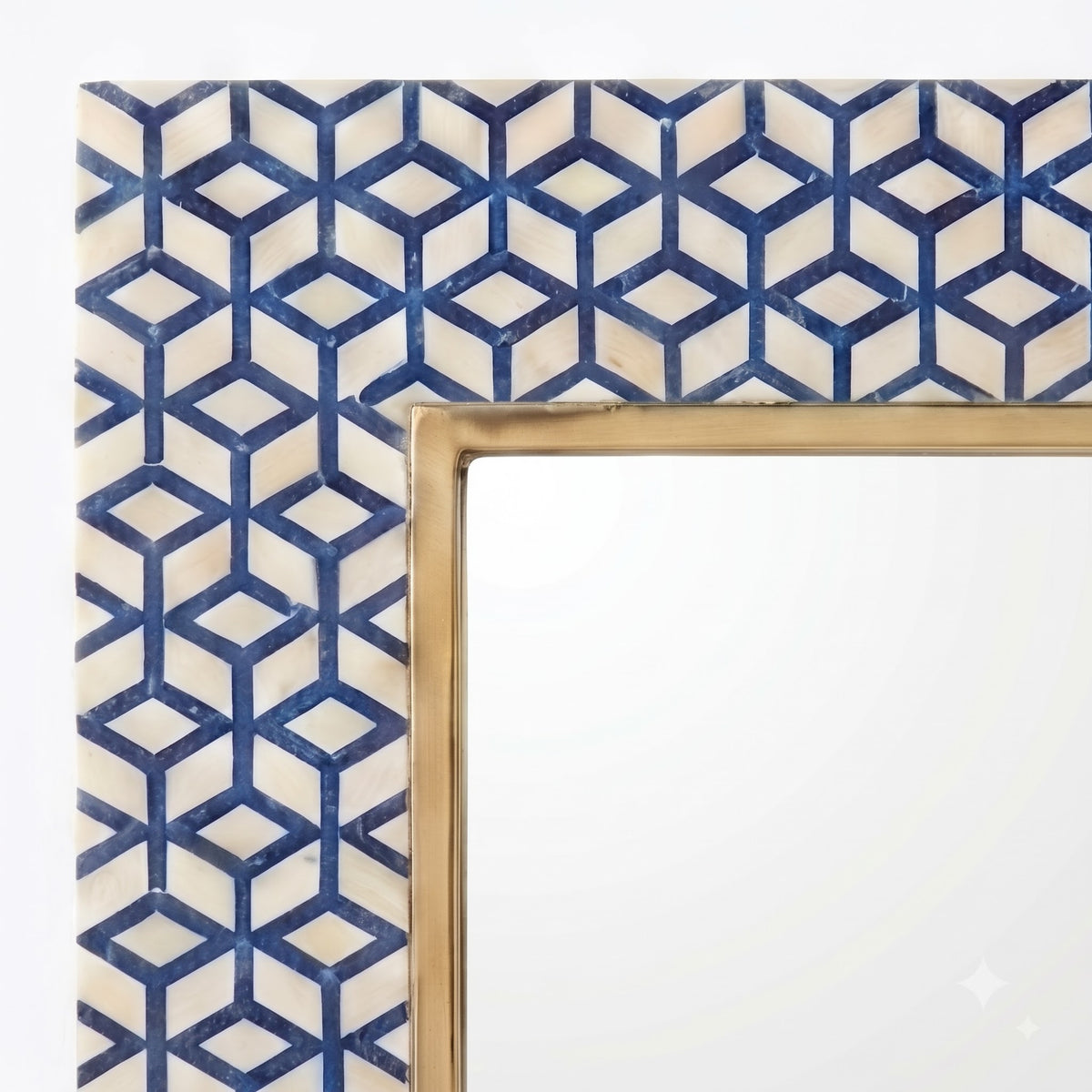A close-up of a decorative mirror frame corner featuring a cream and navy blue geometric cube pattern border with a gold-toned inner frame.