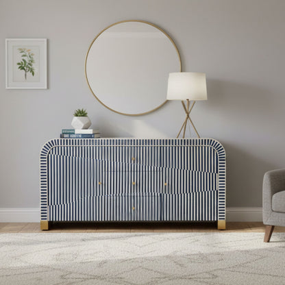 Modern interior with a striped dresser, round mirror, and lamp.