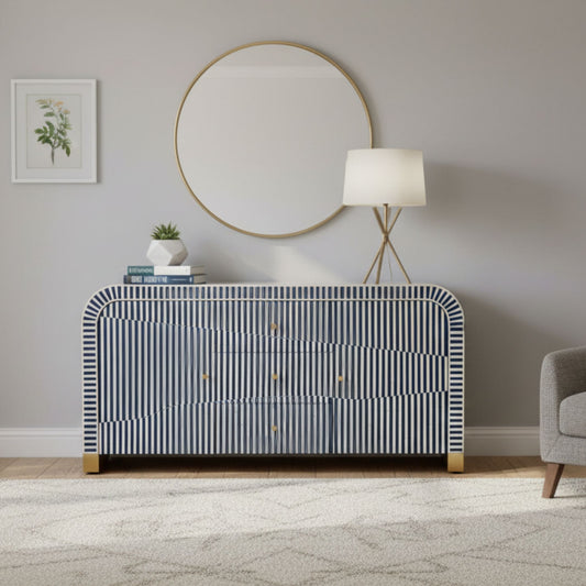 Modern interior with a striped dresser, round mirror, and lamp.
