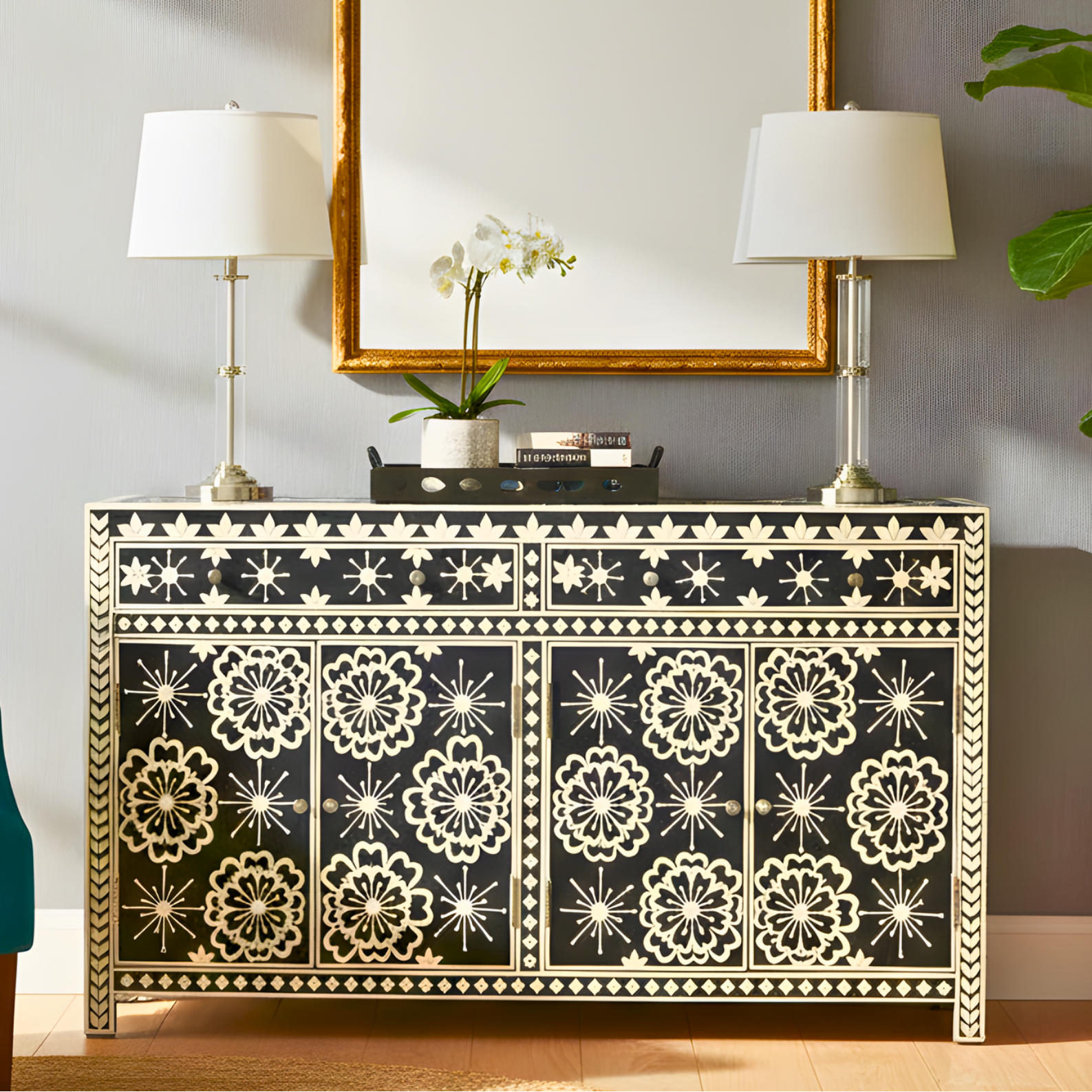 Decorative console table with floral patterns, gold-framed mirror, and lamps in a room setting.