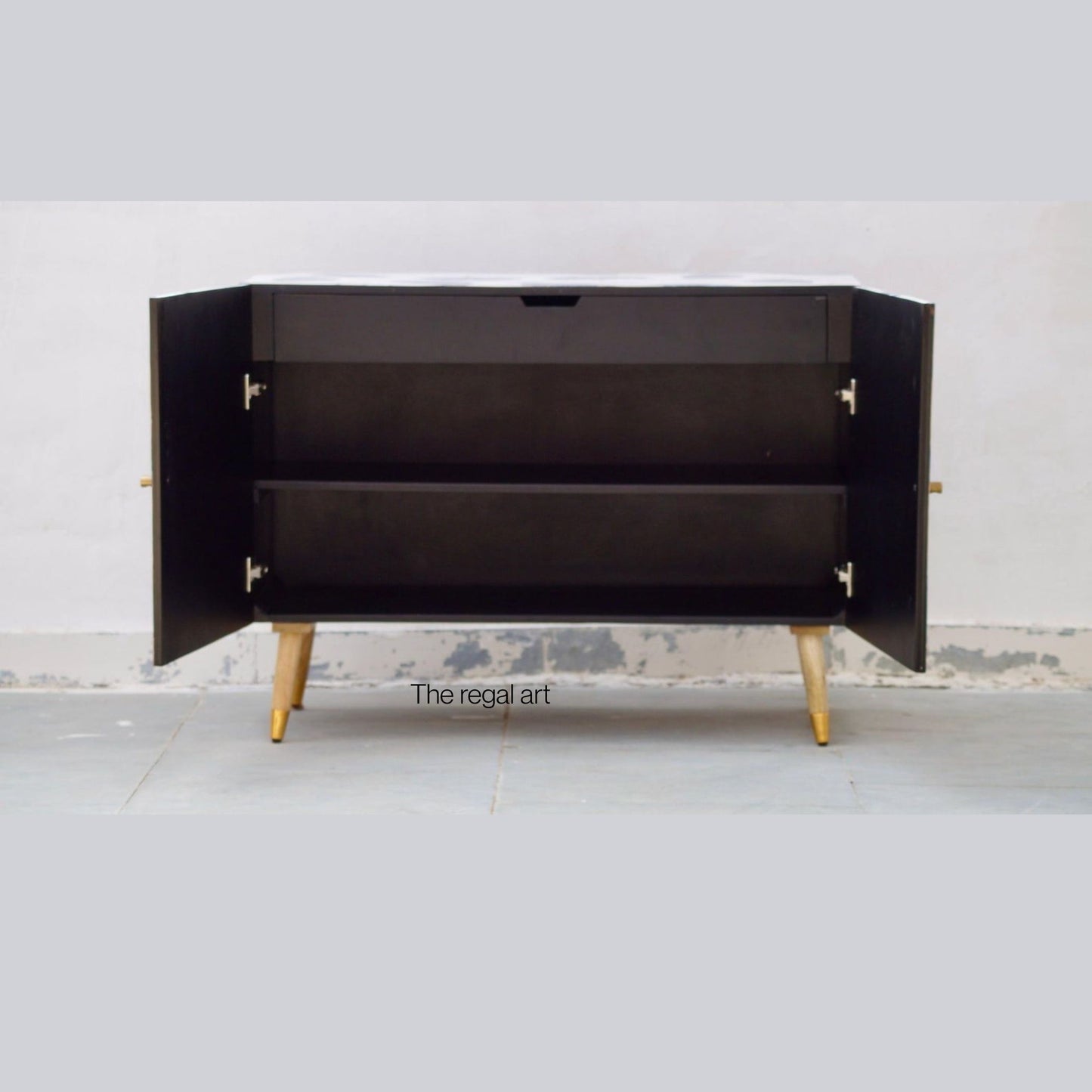 Black cabinet with open doors on a white floor and light gray wall background