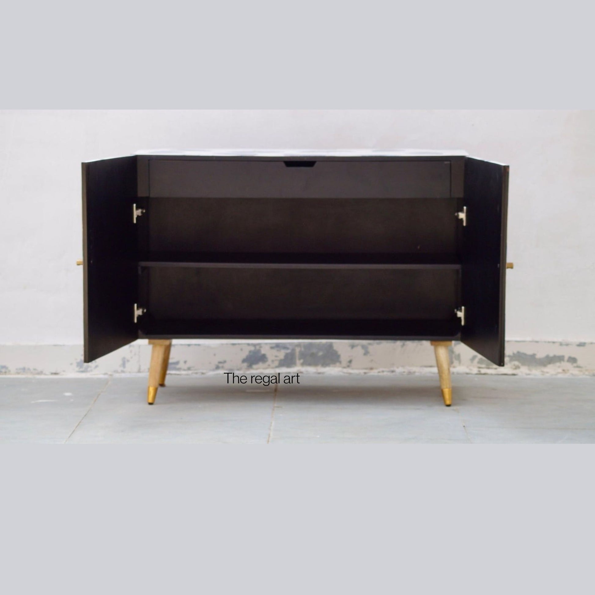 Black cabinet with open doors on a white floor and light gray wall background