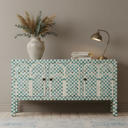 Decorative cabinet with mosaic pattern, vase with plants, and lamp on a wooden floor.