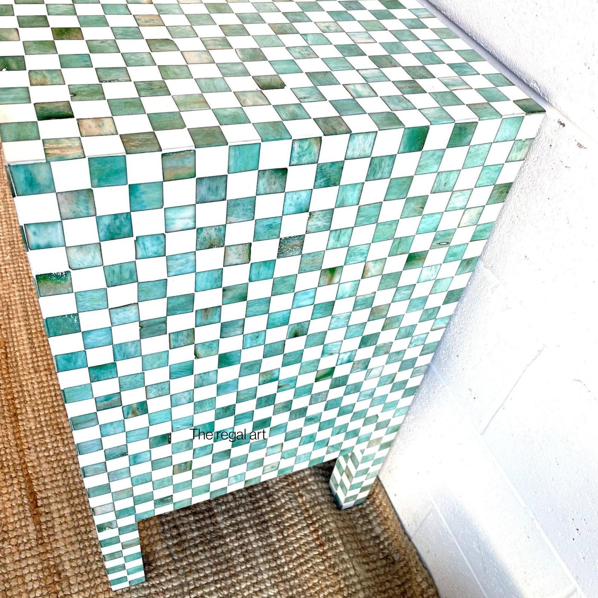 Mosaic patterned side table with green and white tiles on a wooden floor.