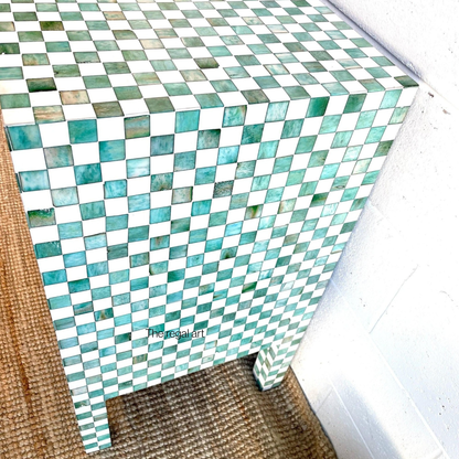 Mosaic patterned side table with green and white tiles on a wooden floor.